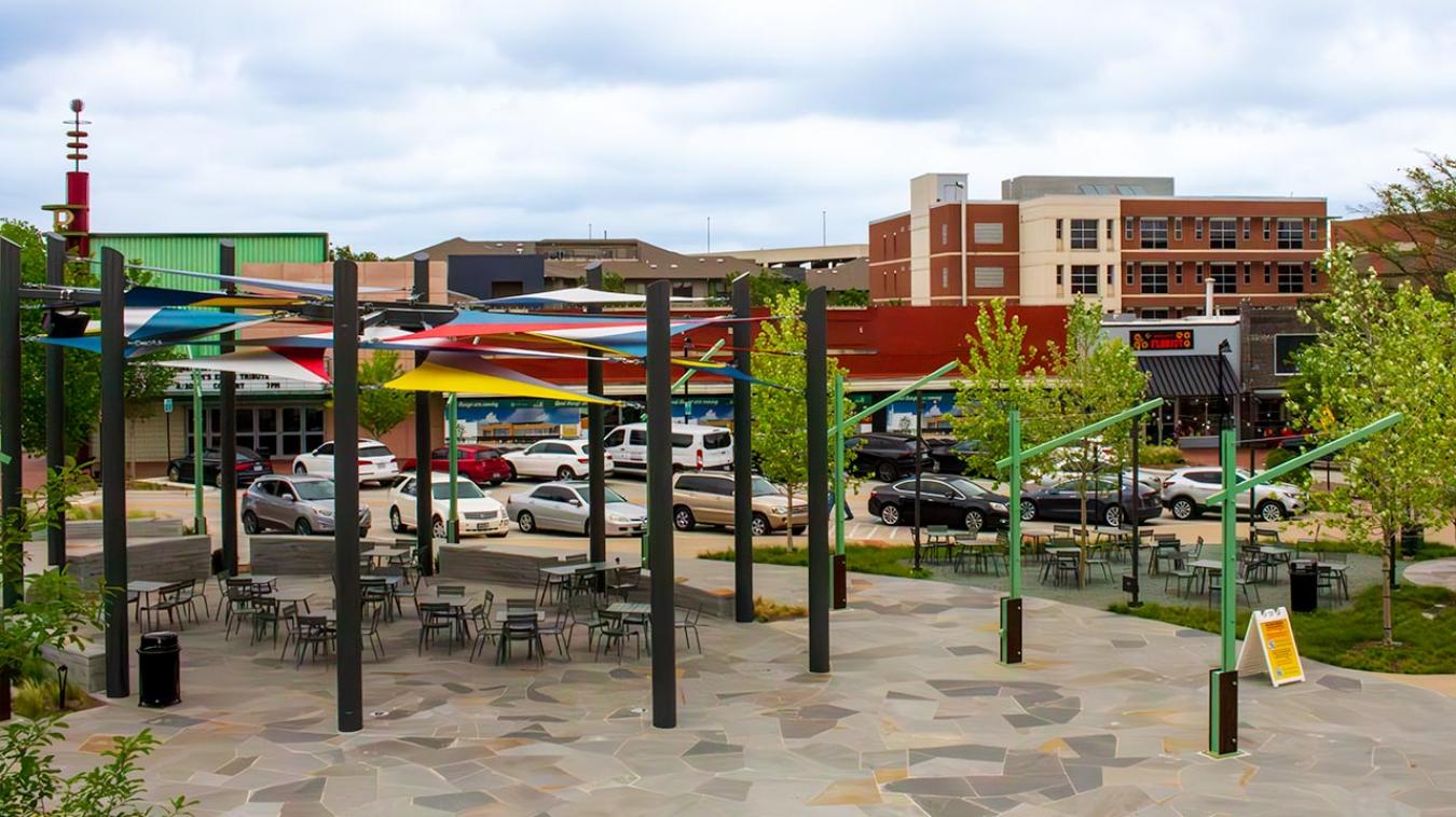 A quaint downtown area featuring old buildings with shops, a 50's style movie theatre, and colorful sunshields creating a nice sitting area.